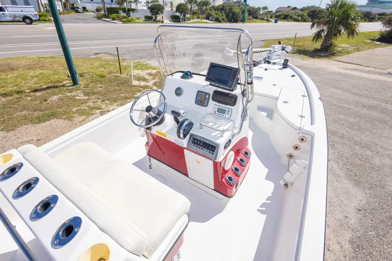Slide: The Image of 2003 Triton 220 LTS boat with steering console and seating, parked near a road. - 26