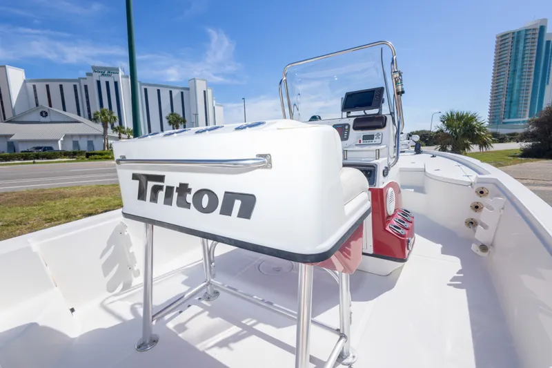 Slide: The Image of 2003 Triton 220 LTS boat interior with console, parked near modern buildings. - 45