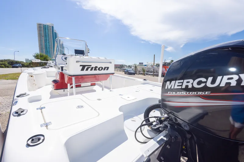 Slide: The Image of 2003 Triton 220 LTS boat with Mercury FourStroke engine, parked near a tall building. - 22