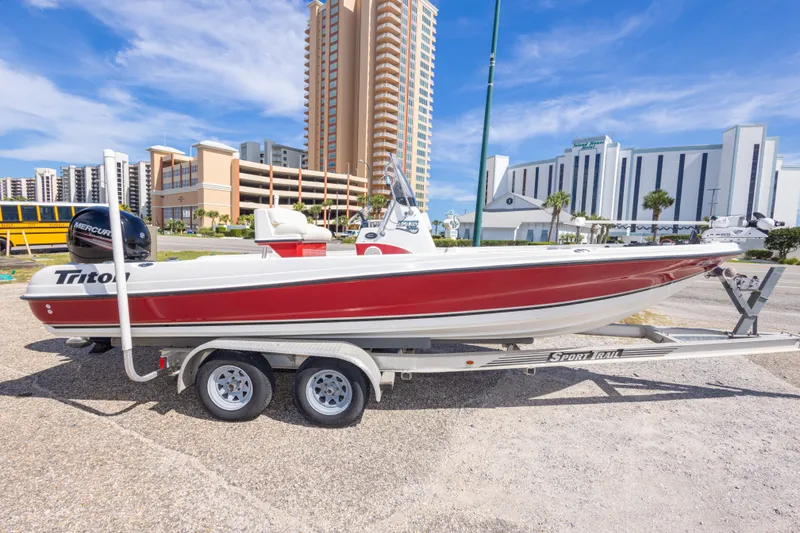 Slide: The Image of 2003 Triton 220 LTS boat on trailer, urban backdrop, clear sky. - 9