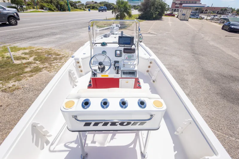 Slide: The Image of 2003 Triton 220 LTS boat interior with steering console and seating, parked on a sunny day. - 25