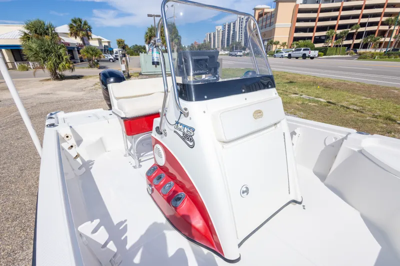 Slide: The Image of 2003 Triton 220 LTS boat with center console, parked near a road and buildings. - 39