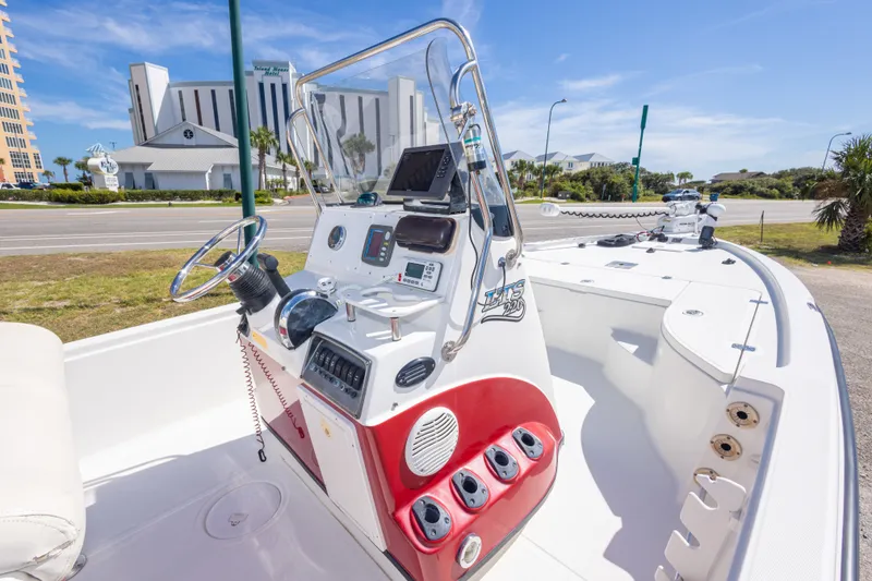 Slide: The Image of 2003 Triton 220 LTS boat with modern console, parked near a coastal road. - 32