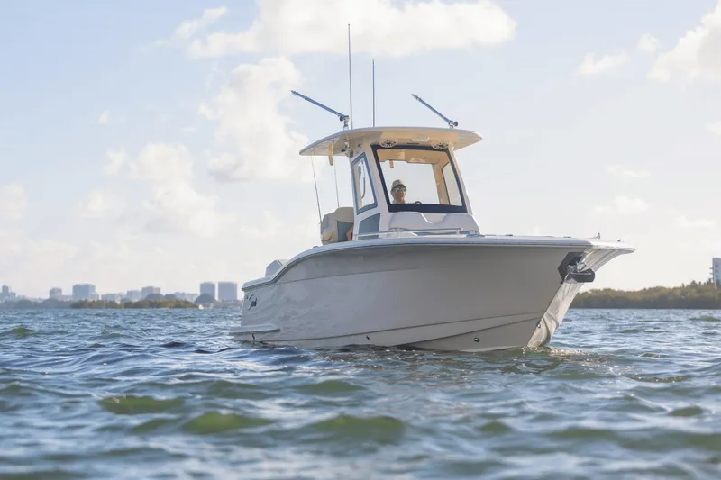 Slide: The Image of A 2027 Scout 260 LXF boat cruising on calm waters with a city skyline in the background. - 13