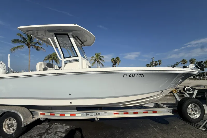 Slide: The Image of 2023 Robalo 266 Cayman boat on trailer, palm trees in background. - 8