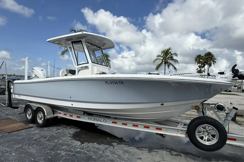 The Image of 2023 Robalo 266 Cayman boat on trailer, parked outdoors under cloudy sky. - 1