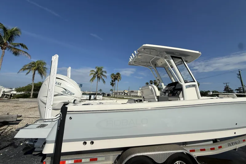 Slide: The Image of 2023 Robalo 266 Cayman boat on trailer, palm trees in background, clear blue sky. - 6
