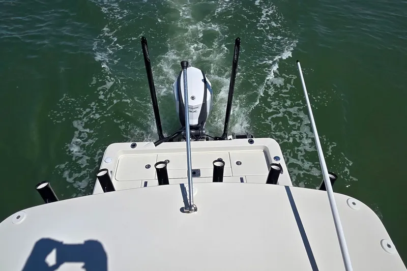 Slide: The Image of 2016 Ranger 2510 Bay Ranger boat on water, rear view with motor and fishing rod holders. - 43