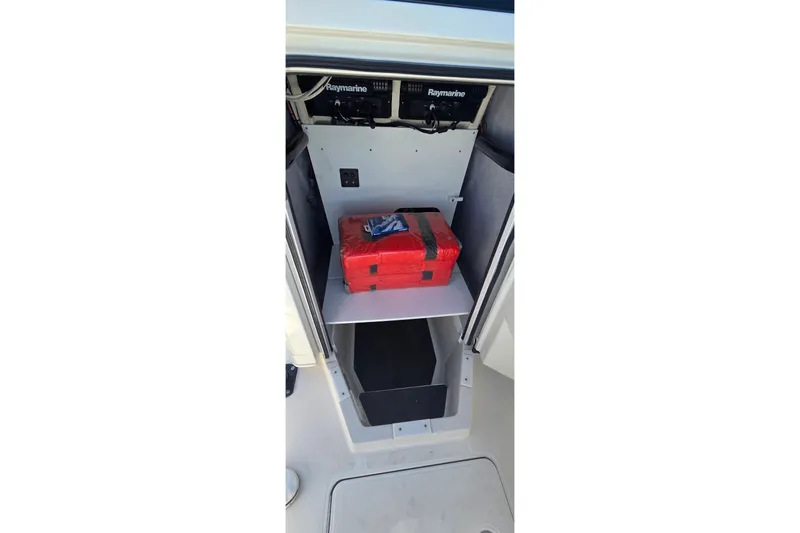 Slide: The Image of 2016 Ranger 2510 Bay Ranger storage compartment with Raymarine electronics and red emergency kit. - 25