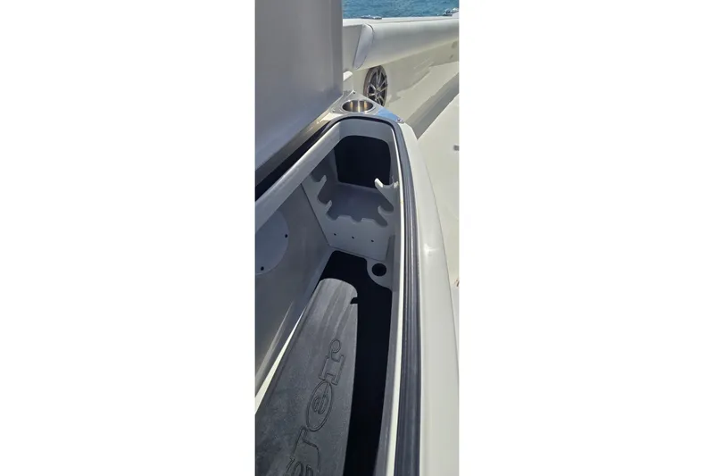 Slide: The Image of 2016 Ranger 2510 Bay Ranger boat storage compartment with rod holders, open on a sunny day. - 29