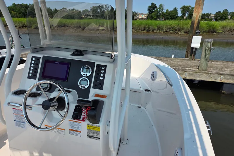 Slide: The Image of 2025 Robalo R180 Center Console boat at dock, featuring modern helm controls. - 24