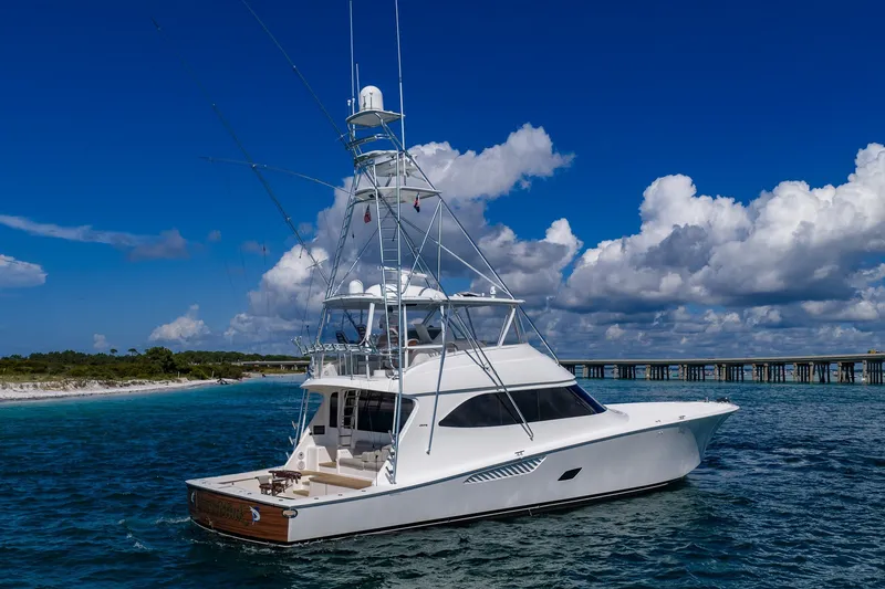 Slide: The Image of 2012 Viking 76 Convertible yacht cruising near a scenic coastline under a blue sky. - 8