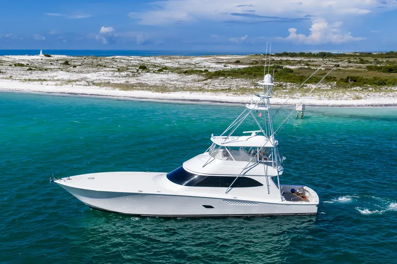 Slide: The Image of Luxury 2012 Viking 76 Convertible yacht cruising in turquoise waters near a sandy shoreline. - 1