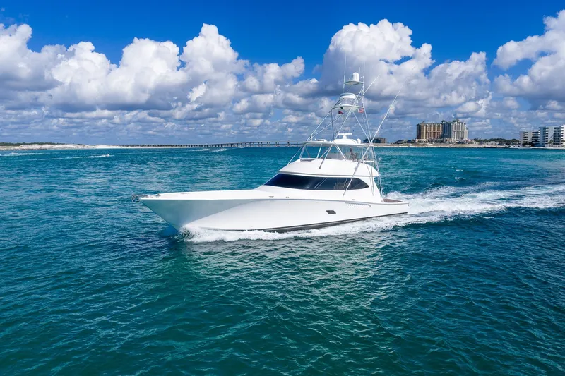 Slide: The Image of 2012 Viking 76 Convertible yacht cruising on clear blue ocean under a partly cloudy sky. - 13