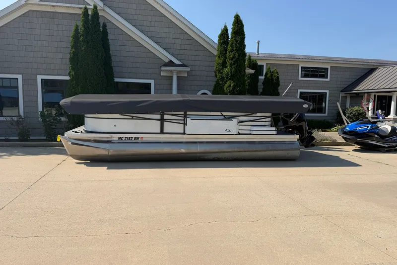 Slide: The Image of 2022 Crest Classic DLX 220 SLC pontoon boat parked outside a building. - 2