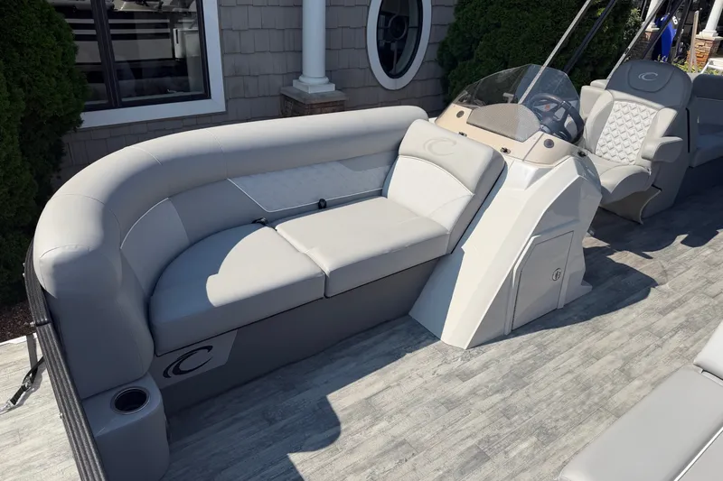 Slide: The Image of 2022 Crest Classic DLX 220 SLC pontoon boat interior with plush seating and helm. - 7