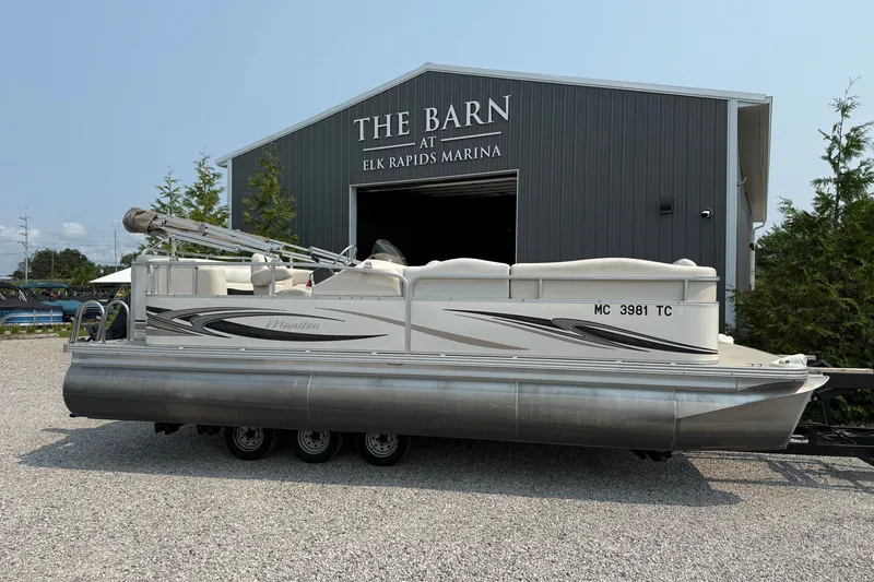 The Image of 2008 Manitou Oasis pontoon boat at Elk Rapids Marina, parked on gravel. - 1