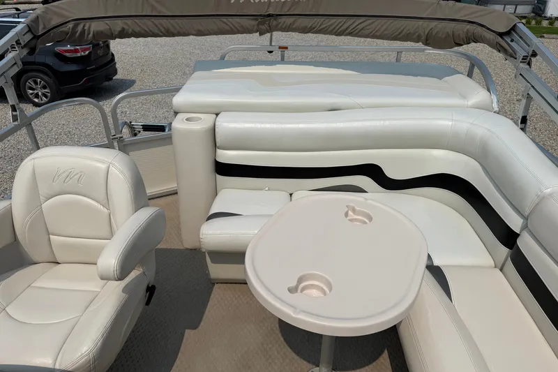 Slide: The Image of 2008 Manitou Oasis boat interior with white seating and table, showcasing luxury and comfort. - 11
