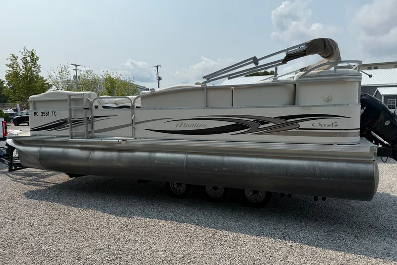 Slide: The Image of 2008 Manitou Oasis pontoon boat parked on gravel lot under cloudy sky. - 7