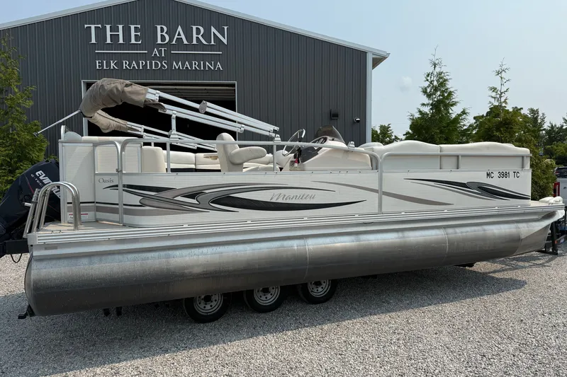 Slide: The Image of 2008 Manitou Oasis pontoon boat at Elk Rapids Marina, parked on gravel. - 2