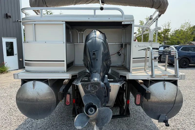 Slide: The Image of 2008 Manitou Oasis pontoon boat with outboard motor, parked on gravel. - 4