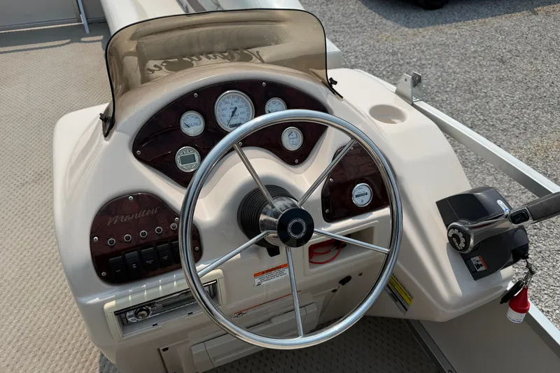 Slide: The Image of 2008 Manitou Oasis boat dashboard with steering wheel and control panel. - 12