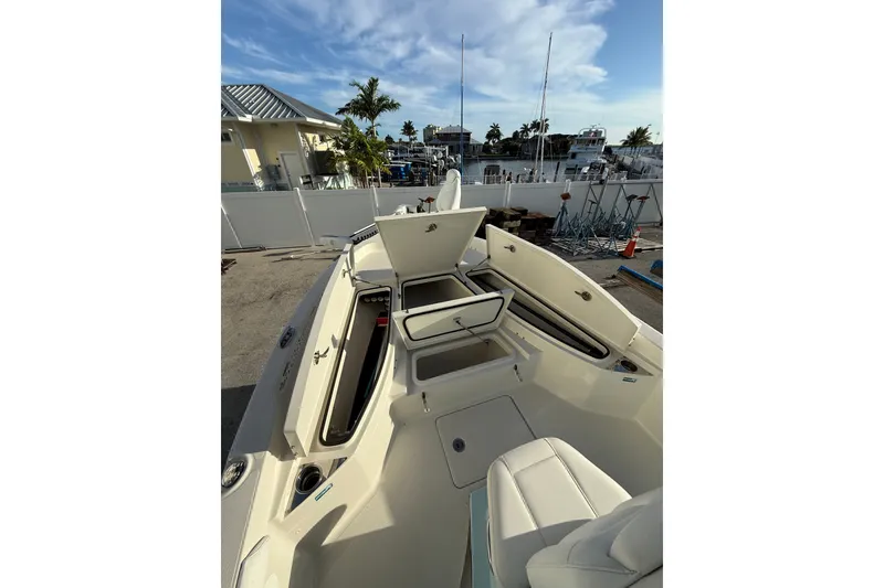 Slide: The Image of 2017 Ranger 2510 Bay Ranger boat with open storage compartments, docked under a clear sky. - 7
