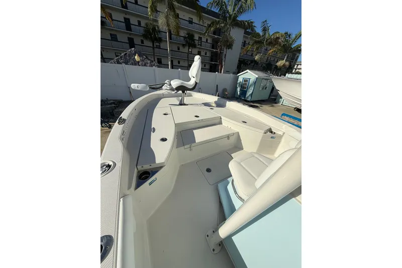 Slide: The Image of 2017 Ranger 2510 Bay Ranger boat interior with seating and storage, docked near palm trees. - 6