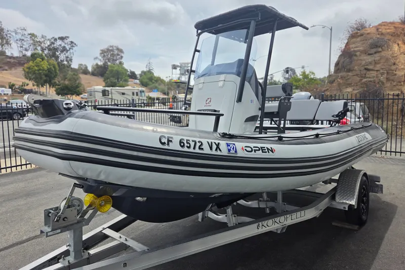 Slide: The Image of 2023 Zodiac Open 5.5 boat on trailer, parked outdoors with scenic background. - 1