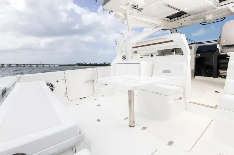 Slide: The Image of Manufacturer Provided Image: 2025 Pursuit OS 405 Offshore boat interior with sleek white seating and table. - 13
