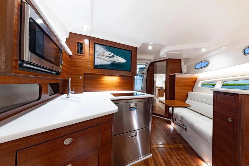 Slide: The Image of Manufacturer Provided Image: Luxurious interior of 2025 Pursuit OS 405 Offshore yacht with modern kitchen and seating area. - 16
