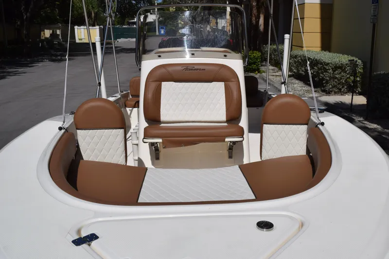 Slide: The Image of 2025 Pioneer 180 Islander boat with brown and white seating, docked outdoors. - 10