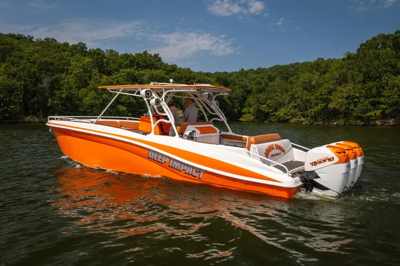 Slide: The Image of Orange and white 2007 Deep Impact 360 C boat cruising on a lake with forested shoreline. - 55