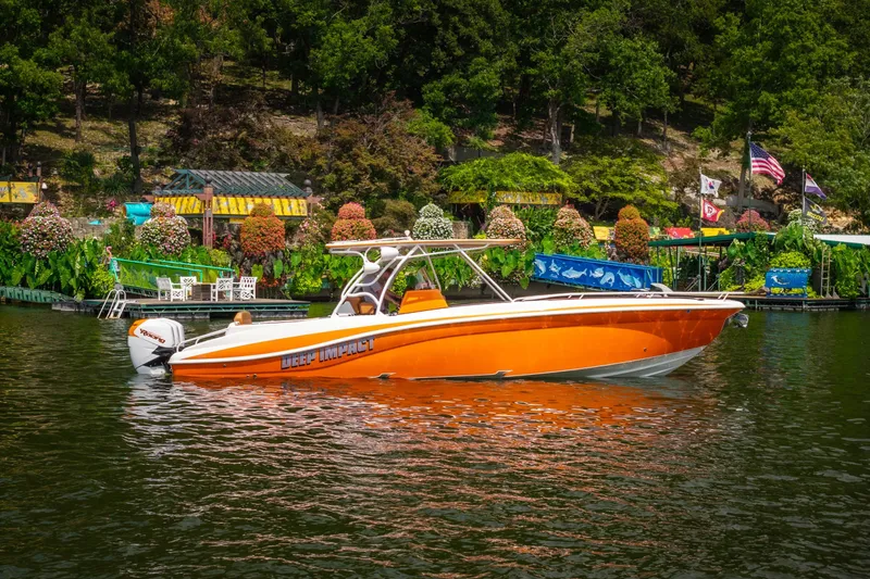 Slide: The Image of Orange 2007 Deep Impact 360 C boat on a scenic lake with lush greenery. - 59