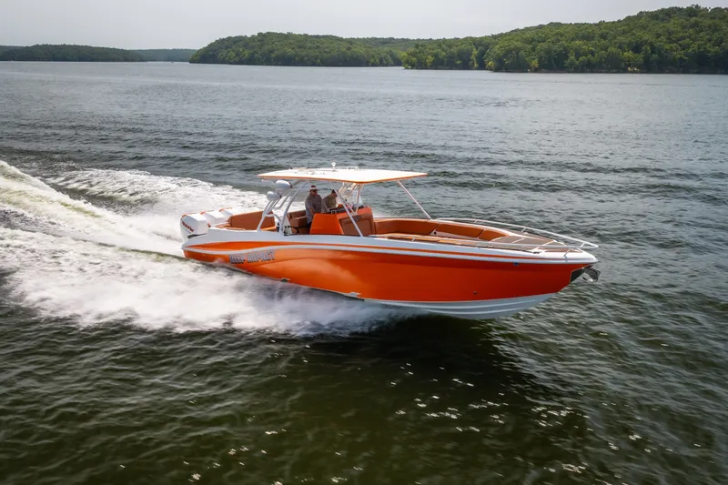 Slide: The Image of Orange 2007 Deep Impact 360 C boat cruising on a lake with lush green shoreline. - 52