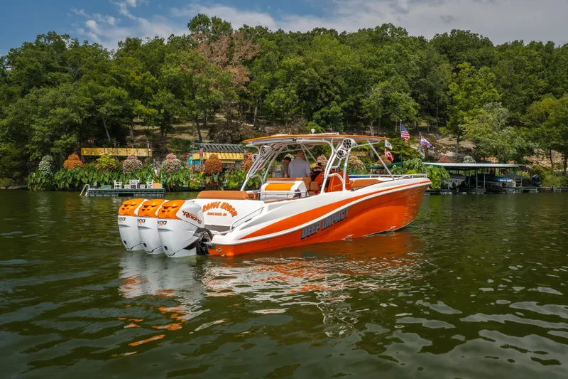 Slide: The Image of Orange 2007 Deep Impact 360 C boat on a lake with lush green background. - 60