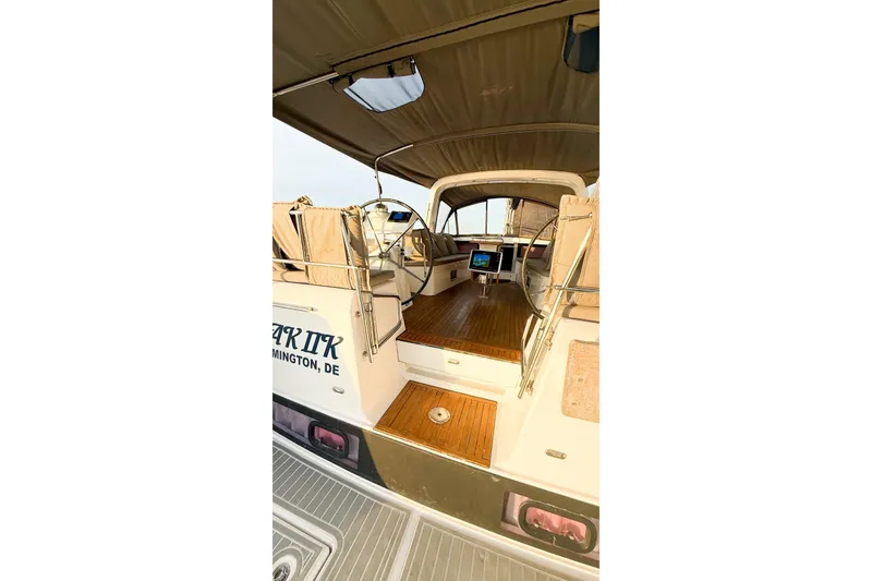 Slide: The Image of 2013 Beneteau Oceanis 48 yacht cockpit with wooden flooring and covered seating area. - 13