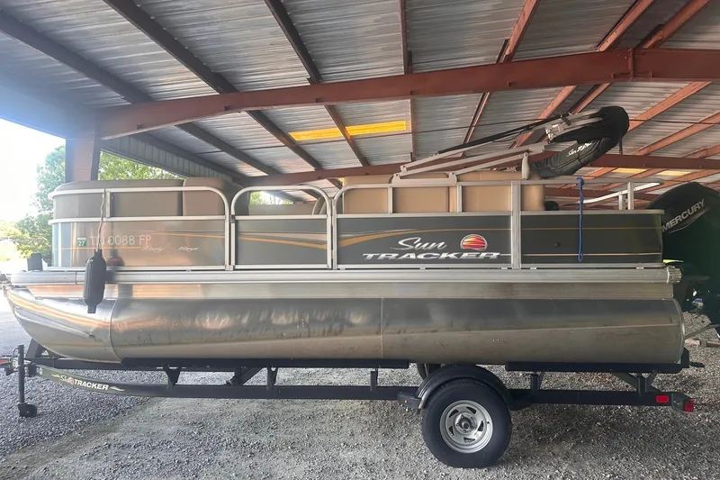 Slide: The Image of 2023 Sun Tracker Party Barge 18 DLX pontoon boat on trailer in covered storage. - 13