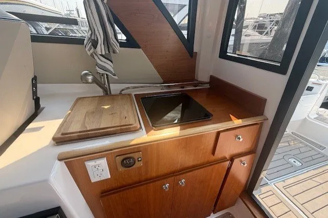 Slide: The Image of 2025 Cutwater C-248 Coupe interior kitchen with wooden cabinetry, sink, and stovetop. - 13