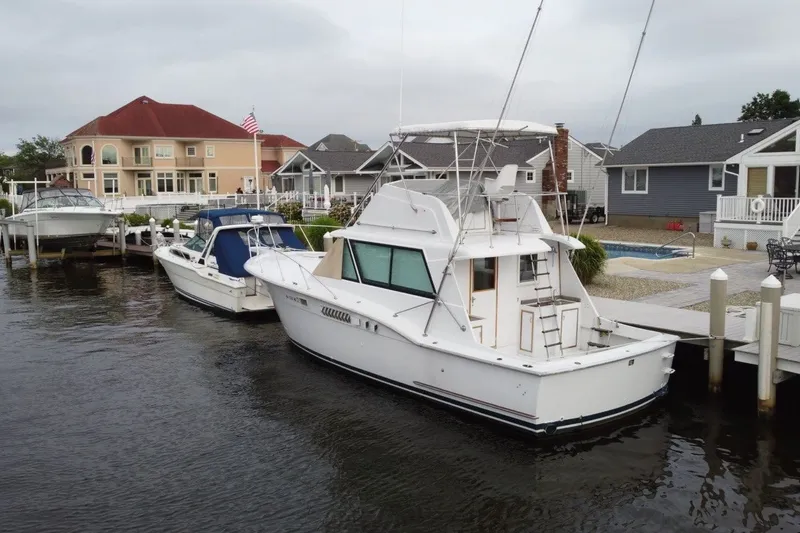 Slide: The Image of 1968 Hatteras 38 Convertible yacht docked near waterfront homes. - 2