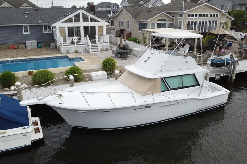 The Image of 1968 Hatteras 38 Convertible yacht docked by waterfront homes and a swimming pool. - 1