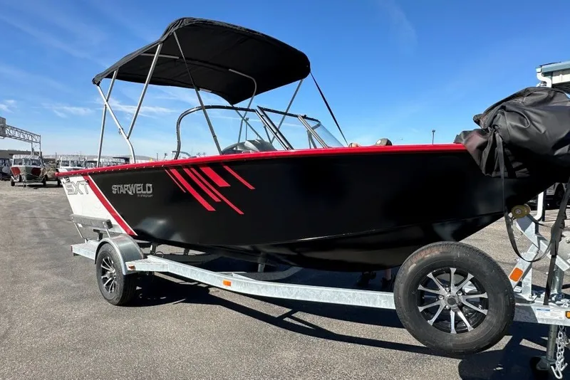 Slide: The Image of 2026 Starweld 18 SXT boat on trailer, black with red accents, under clear blue sky. - 2