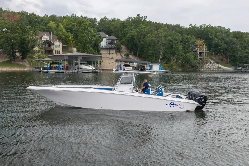 The Image of 2018 Fountain 38 Center Console boat cruising on a lake near waterfront homes. - 1