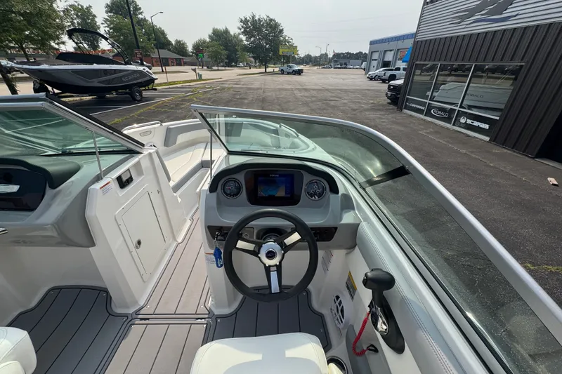 Slide: The Image of 2023 Chaparral 21 SSi boat interior with steering wheel and dashboard, parked outside dealership. - 29