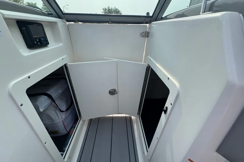 Slide: The Image of 2023 Chaparral 21 SSi boat interior storage compartment with open doors. - 23