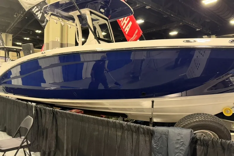 The Image of 2025 Yamaha Boats 255 FSH Sport E displayed indoors, showcasing sleek blue hull design. - 1