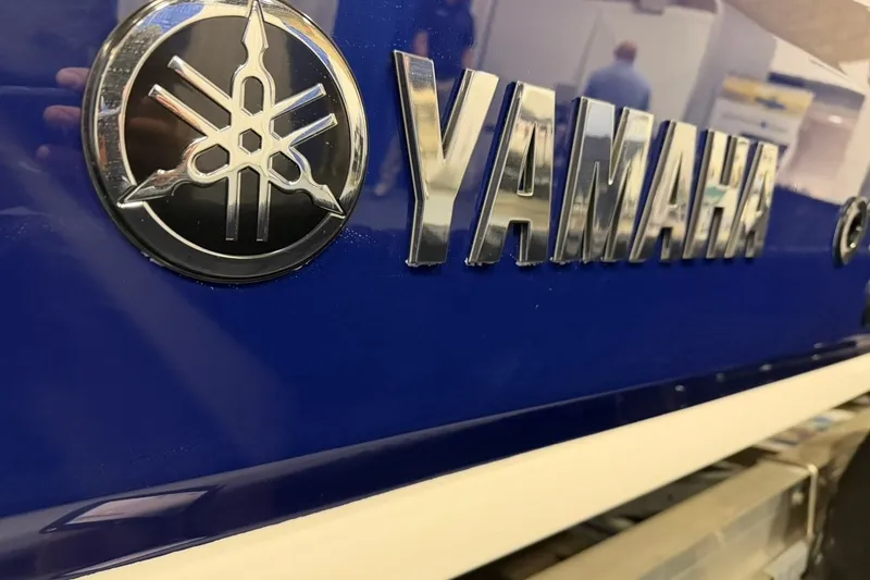 Slide: The Image of Close-up of 2025 Yamaha Boats 255 FSH Sport E logo on blue surface. - 2