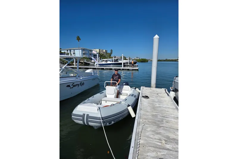 Slide: The Image of Inflatable Caribe CL14 boat docked at marina, clear blue sky, 2026 model. - 1