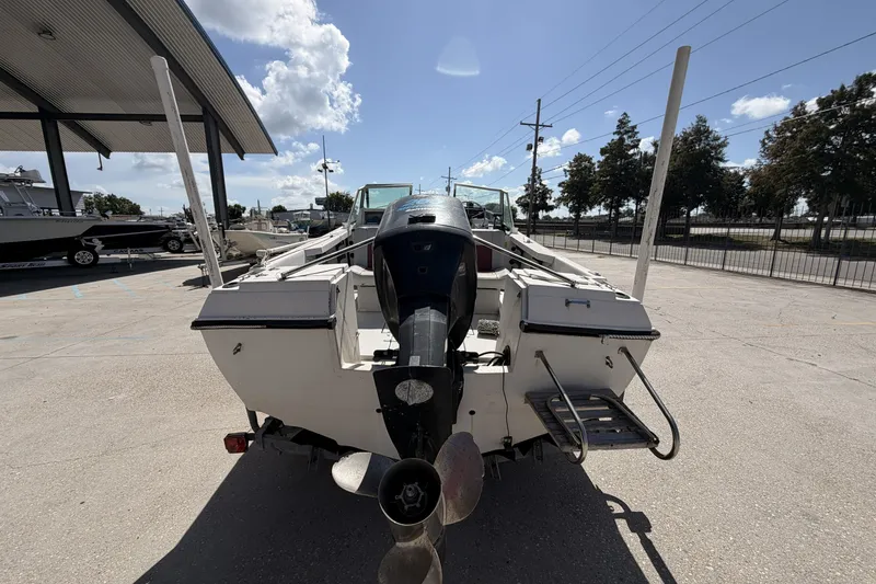 Slide: The Image of 1988 Wellcraft 200 Fisherman boat with outboard motor, parked outdoors under a sunny sky. - 3