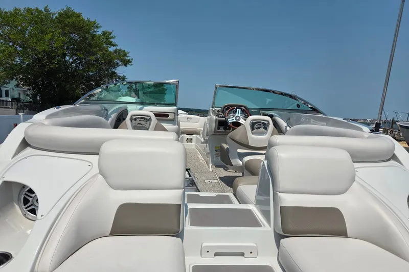 Slide: The Image of 2015 Crownline 255 SS boat interior with white seating and steering wheel, under clear blue sky. - 17